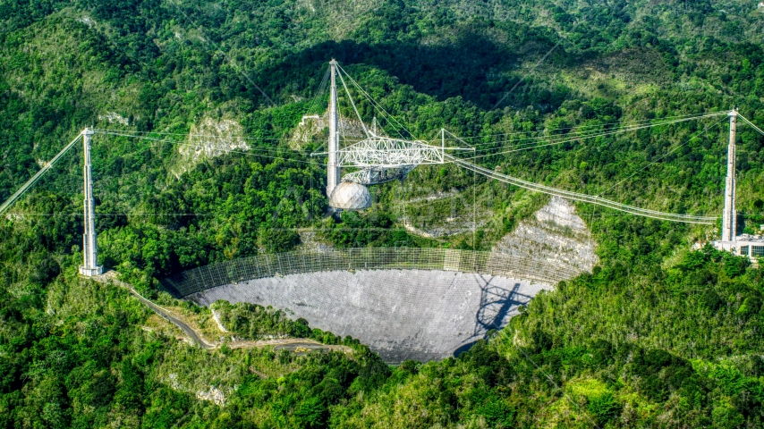 The dish of the Arecibo Observatory among lush green jungle, Puerto Rico Aerial Stock Photo AX101_090.0000342F | Axiom Images